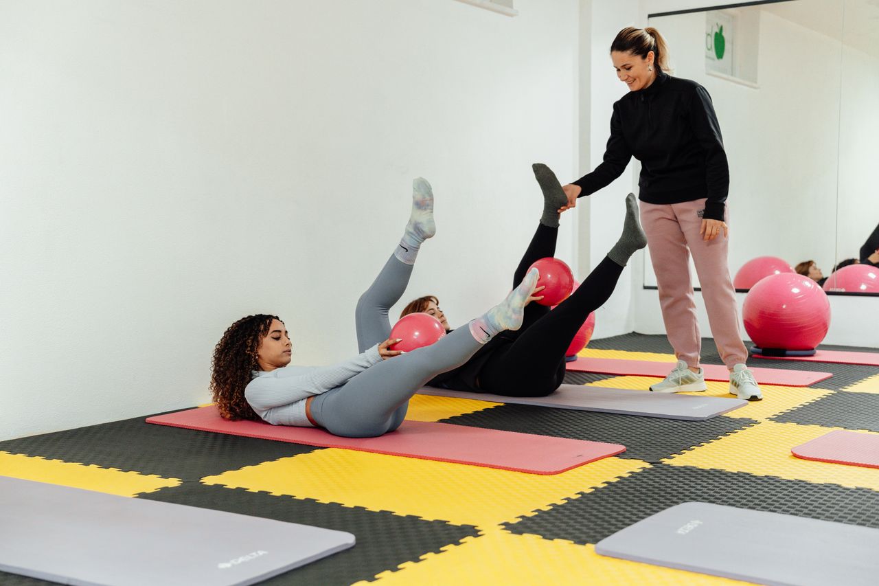 Crafting Captivating Headlines: Your awesome post title goes here Women engaged in pilates class using pink balls and yoga mats indoors at a gym.